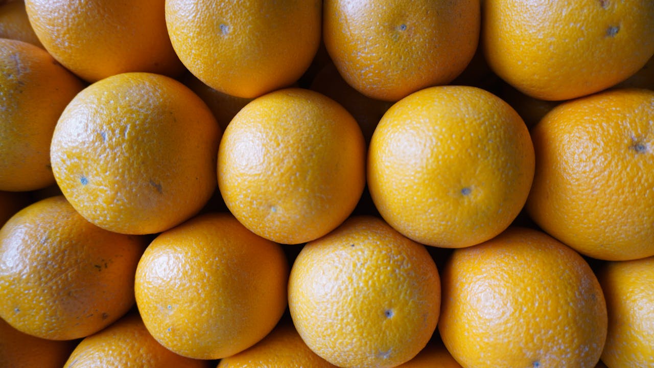 heros-img A top-down view of fresh oranges stacked in a market in Pune, India.